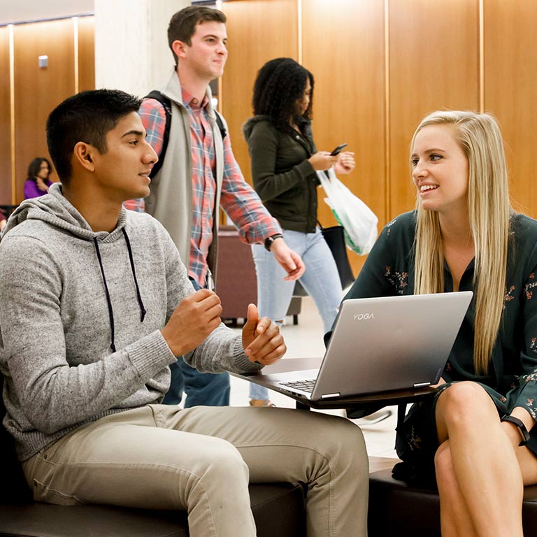 Two students talk in the library.